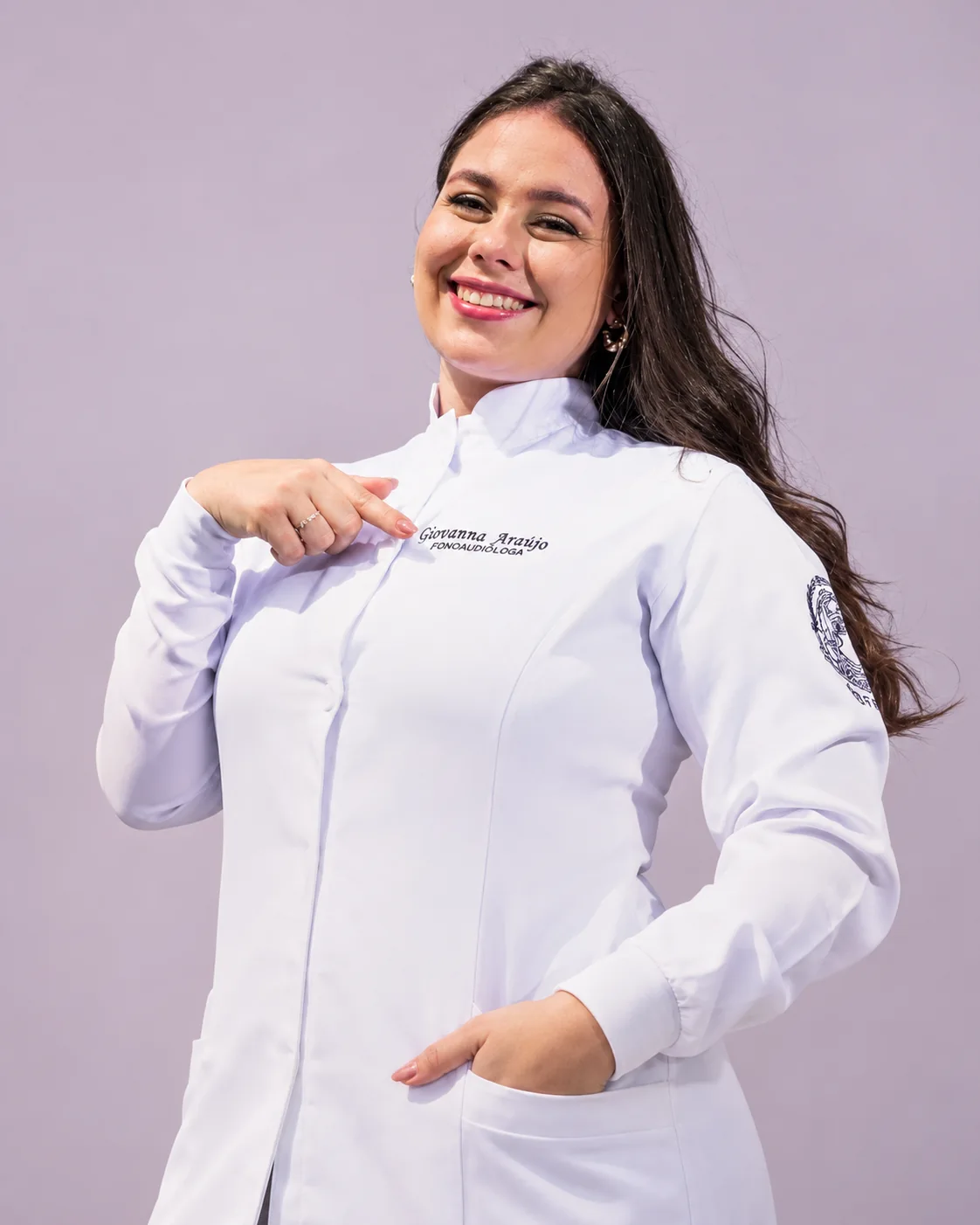 Giovanna Araújo sorrindo, com seu jaleco de fonoaudióloga